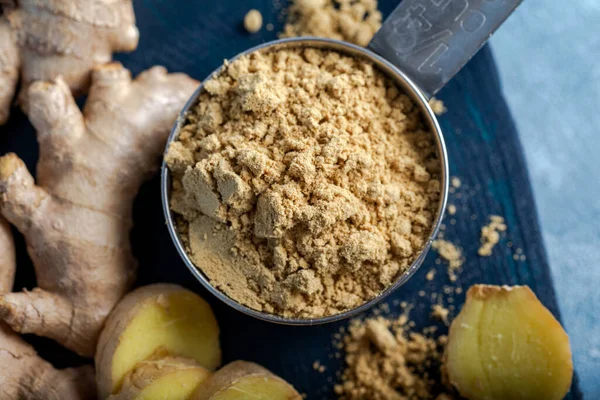 Ginger root and ginger powder in the bowl. Fresh ginger root and ground ginger spice.