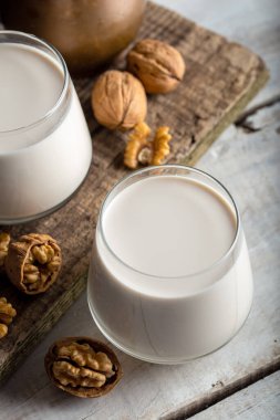 Organik ceviz ve ahşap arka planda bir bardak ceviz sütü..