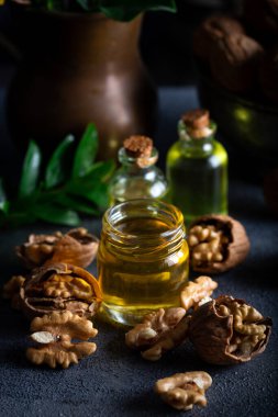 Ahşap arka planda kozmetik ve terapi amaçlı ceviz yağı. Şişede ceviz yağı, arka planda fındık..