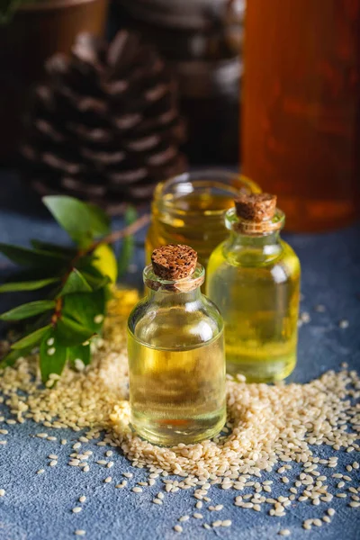 Sesame oil in glass and seeds. Fresh sesame oil in a glass bottle and seeds on blue background.