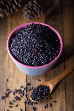 Ahşap arka planda seramik kasede siyah pirinç. Tayland siyah yasemin pilavı (Rice berry).