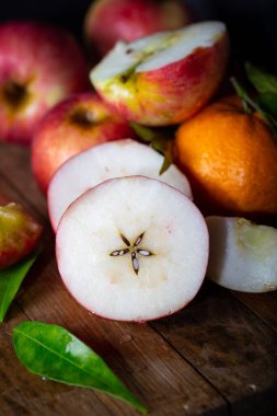 Taze kırmızı elmalar, bir bütün, ve kırsal ahşap zemine konmuş yarımlar..