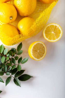 Beyaz arka planda limon olan ağ alışveriş torbası. Yapraklı limon dilimleri.. 