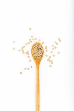 Beyaz arka planda izole edilmiş tahta kaşıkta yeşil mercimek..