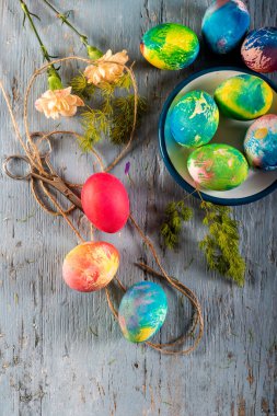 Mavi ahşap bir masada renkli paskalya yumurtaları. Üst görünüm.