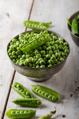 Fresh green peas. Fresh green peas pods and green peas in bowl on wooden background.