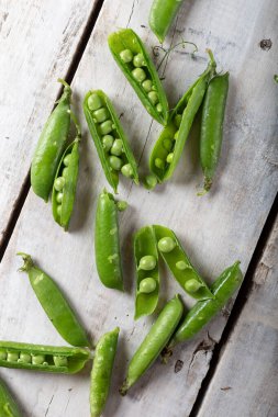 Open, fresh green sweet pea pods on a wooden table. Fresh green peas.