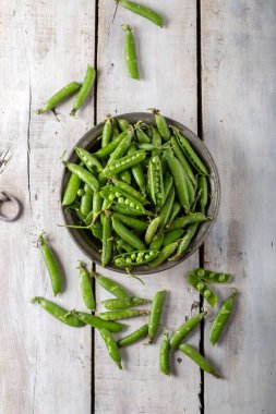 Fresh green peas. Fresh green peas pods and green peas in bowl on wooden background.