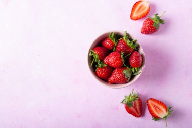 Fresh strawberries in pink bowl on pink background. Top view.