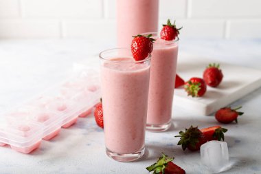 Taze ev yapımı, buzlu ve beyaz arka planda taze çilekli soğuk çilekli smoothie..