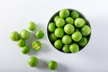 Beyaz kasede taze yeşil erikler. Üst görünüm.