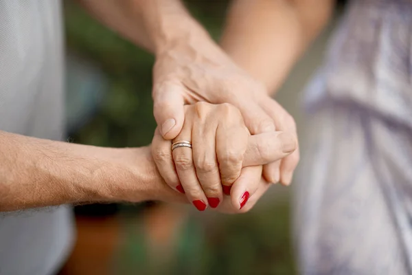 Przycięte ujęcie starszej pary trzymającej się za ręce w parku — Zdjęcie stockowe