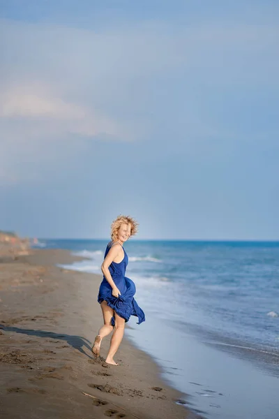 Retrato de cuerpo entero de una joven riéndose y corriendo por la playa — Foto de Stock