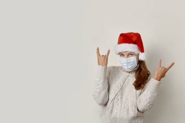 Noel Baba şapkalı kadın elleri havada rock sembolü yapıyor.