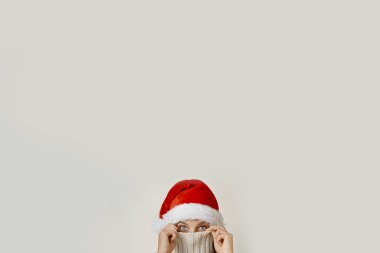 Noel Baba şapkalı bir kadın tasmasıyla yüzünü kapatıyor.
