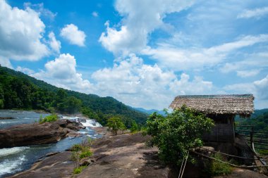 Dağdaki şelalelerin yanında küçük bir kulübe Mavi ve beyaz bulutlu gökyüzünün altında Kerala şelalesi