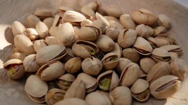 Pistachios fall into a wooden plate. Nutritious nuts, pistachios in a healthy diet.