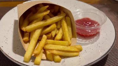 Yakınlarda soslu karton bir kutudan çıtır patates kızartması toplayan bir kadının yakın çekimi. Fast food kavramı, sağlıksız yeme alışkanlıkları ve hızlı atıştırmalıklar..