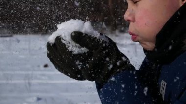 Adam avucunun içinde topladığı karı uçuruyor. Karlı bir kışta eğlence. Karlı bir kışta dinlenmek