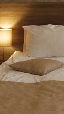 Yatak odasının içi. Yastıklı bir yatak, yanındaki lamba açık. Sakin bir akşamda rahat bir lamba atmosferi.