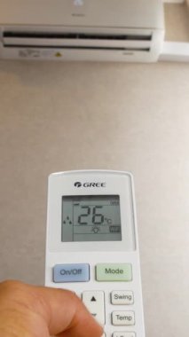 Uzaktan kumanda, duvarda asılı olan klimanın karşısında. Uzaktan kumandanın görüntüsü odadaki sıcaklığın nasıl düştüğünü, klimanın nasıl ayarlandığını gösteriyor.