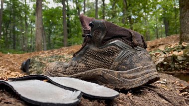 Kharkiv, Ukrayna - Mayıs 04, 2024: Ormandaki bir siperin yakınında kurumuş bir asker botu. Askerlerin hayatı. Savunma yapıları, siperler, ormandaki yaşam. Ekstrem turizm, çadırlarda yaşam.