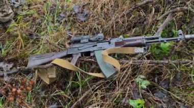 Bir Kalaşnikof saldırı tüfeği ormandaki çimlerin üzerinde yatıyor. Hafif silahlar. Gerçek bir savaş. Russo-Ukrayna savaşı.