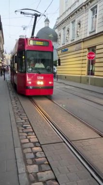 Kharkiv, Ukrayna - 12 Ekim 2025: Tramvay eski Avrupa şehrinin eski dar sokakları boyunca seyahat eder. Yayalar yakınlarda yürüyorlar. Büyük bir şehirde taşıma. Çevresel olarak tramvay