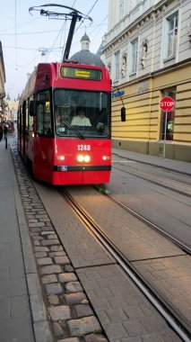 Kharkiv, Ukrayna - 12 Ekim 2025: Tramvay eski Avrupa şehrinin eski dar sokakları boyunca seyahat eder. Yayalar yakınlarda yürüyorlar. Büyük bir şehirde taşıma. Çevresel olarak tramvay
