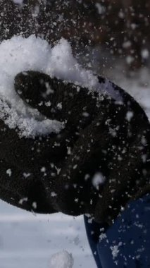 Adam avucunun içinde topladığı karı uçuruyor. Karlı bir kışta eğlence. Karlı bir kışta dinlenmek