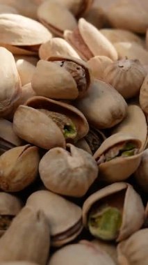 Pistachios fall into a wooden plate. Nutritious nuts, pistachios in a healthy diet.