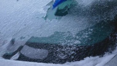 Sürücü kışın arabanın ön camındaki buz tabakasını kazır. Buz kaldırılana kadar araba kullanılmamalıdır. Tehlikeli meteorolojik fenomen, arabanın buzlanması..