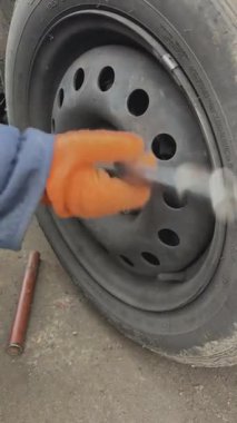 Usta, araba tekerleğindeki cıvataları bir ingiliz anahtarıyla sıkıyor. Tekerlek tamiri. Efendi arabanın direksiyonunu değiştiriyor..