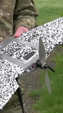 Bir asker elinde pervane ve antenleri olan küçük bir dronu tutuyor ve döndürüyor. Dronlar askeri operasyonlarda silah olarak kullanılıyor. Gerçek savaş, saldırı ve keşif robotlarının kullanılması. Russo.