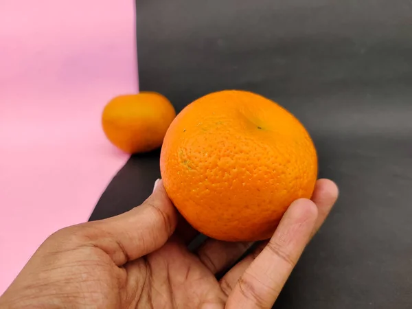 Mão Homem Segurando Uma Fruta Laranja Saborosa Isolada Fundo Rosa — Fotografia de Stock