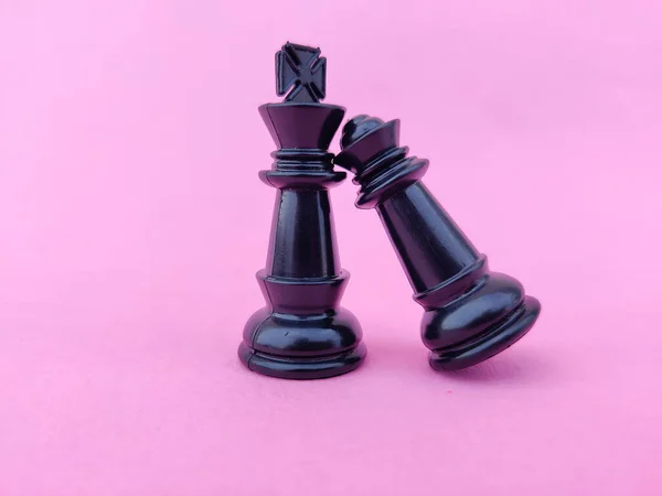 Black chess queen fallen on black chess king\'s shoulder. Valentines day concept