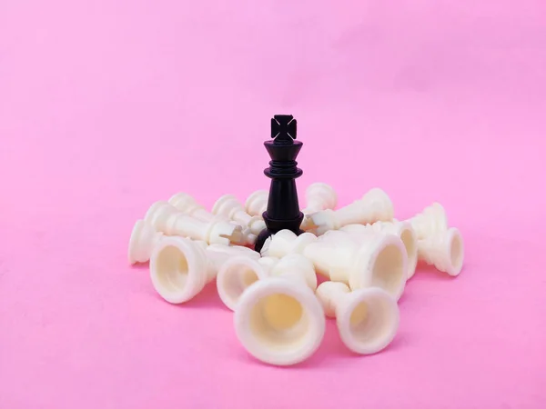 Fekete Sakk Király Körülvéve Bukott Fehér Sakkfigurákkal Rózsaszín Háttér Üzleti — Stock Fotó