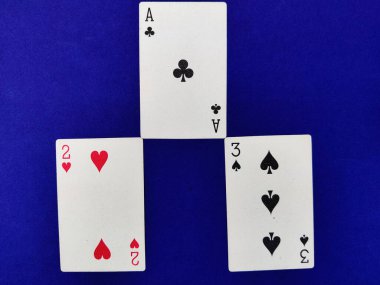 Yonca ası, iki kupa ve maça üçlüsü mavi arkaplanda kağıt oynuyor.