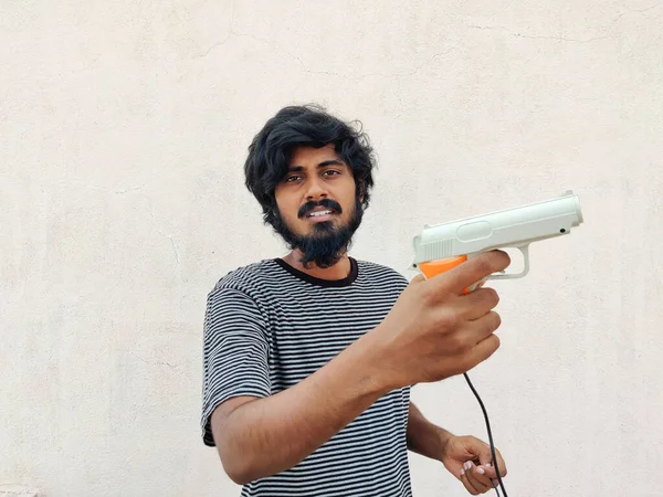 南インドの若いひげ男は白い色のゲームピストル銃を持っている — ストック写真
