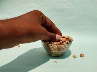 Erkek eller yeşil arka planda cam kaseden fındık topluyor.