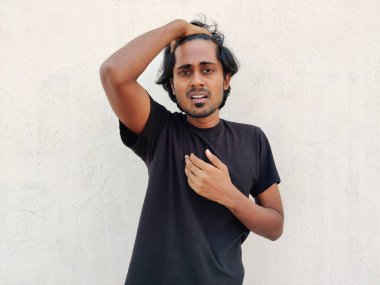 Siyah tişörtlü yakışıklı Tamil adam uzun saçlarını parmaklarıyla tarıyor. Beyaz arkaplan