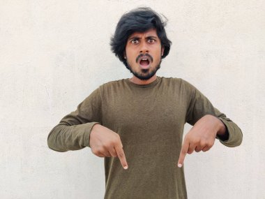 Uzun saçlı Güney Hintli genç adam şok edici bir tepkiyle parmaklarını işaret ediyor. Ağzını geniş aç. Beyaz arkaplan