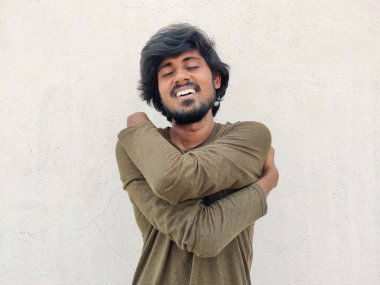 Uzun saçlı, sakallı, gülen genç Hintli Tamil adam kendine ya da kendine sarılıyor. Kişisel bakım. Beyaz arkaplan