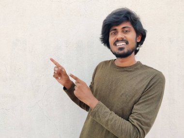 Süper havalı, sakallı, uzun saçlı, resmi kollu ve iki elini sola doğru gösteren genç bir adam. Uzayı kopyala Beyaz arkaplan