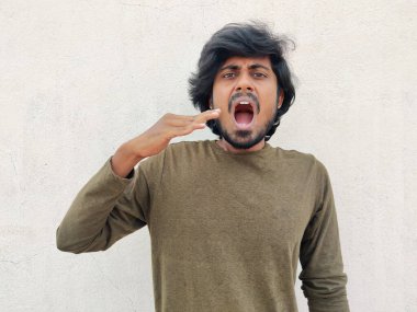 Güney Hintli adam baharatlı yemek yedikten sonra elleriyle dilini serinletmeye çalışıyor. Beyaz arkaplan.