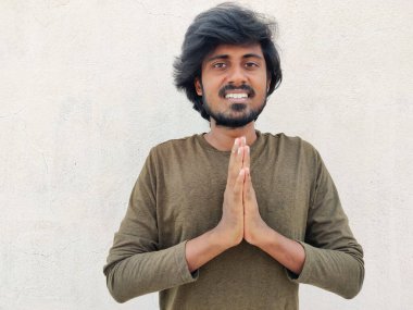 Güney Hintli yakışıklı adam avuçlarını bir arada tutarken hoş geldin ifadesi takınıyor. Vanakkam. Beyaz arkaplan