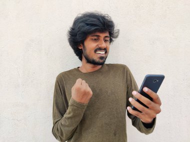 Akıllı telefonuna bakan süper heyecanlı genç adam. Mutlu haberler aldı..