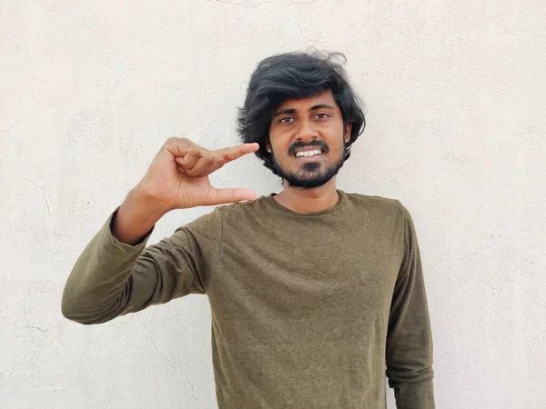 Uzun saçlı, gülümseyen adam parmaklarının arasında küçük bir şey tutuyor. Beyaz arkaplan