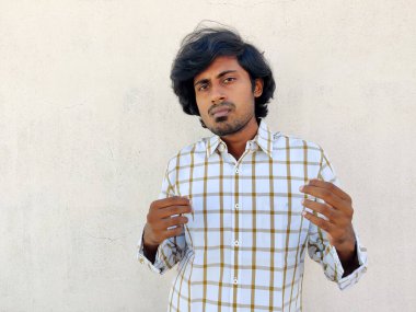 Beyaz gömlekli yakışıklı genç adam. Kameraya doğru sakin görünüyor. Beyaz arkaplan