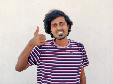 Çizgili tişört giyen genç, gülümseyen Hintli adam bana parmaklarıyla jest yapıyor. Beyaz arkaplan